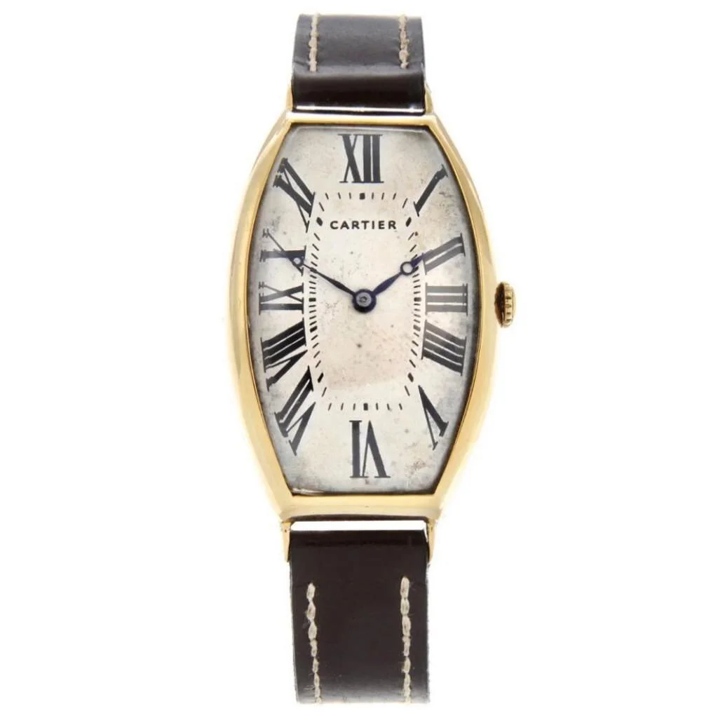 Vintage gold Cartier tonneau watch with cream dial, Roman numerals, and brown leather strap.